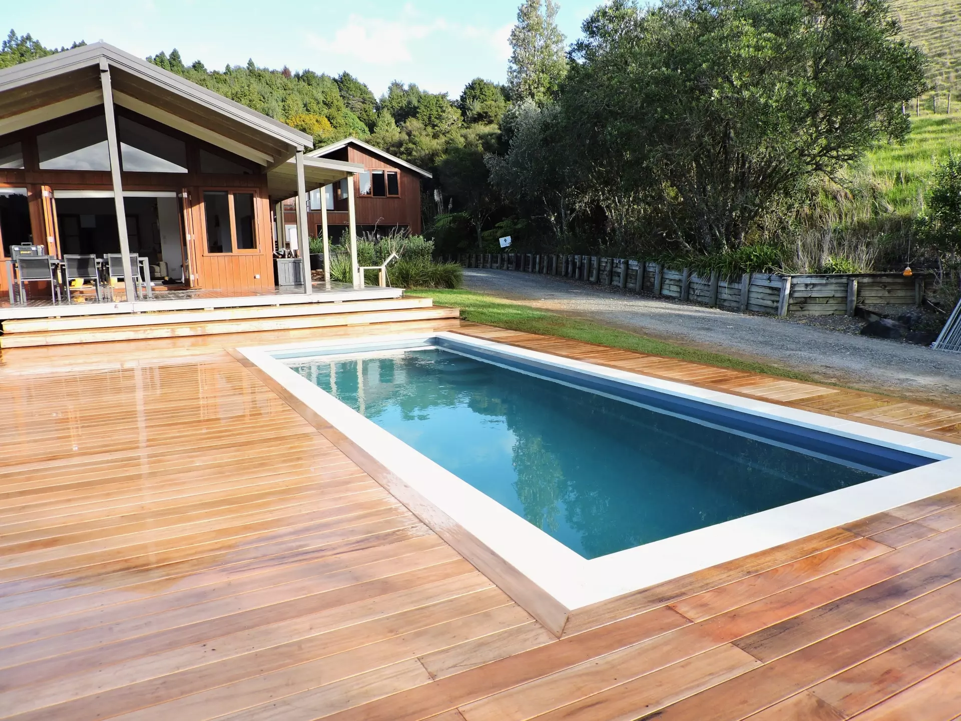 Deck around pool with house in the background